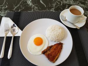 un plato con un huevo y arroz y una taza de café en B&S Orchids suites hotel, en Dipólog