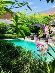 a pool in a garden with some plants and flowers at Villa Bloom 1 - 4 bedrooms, 4 bathrooms, private pool close to the beach in Seminyak