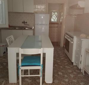 een keuken met een witte tafel en een blauwe stoel bij Villa Frida in Campomarino +7 foto's