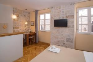 a living room with a tv on a stone wall at Apartments Sunny Town in Korčula