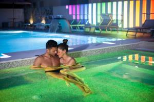 dos personas están sentadas en una piscina en Love Boat Hotel - The Original, en Riccione