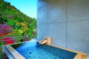 uma banheira de hidromassagem com vista para uma floresta em Arima Onsen Gekkoen Korokan em Kobe