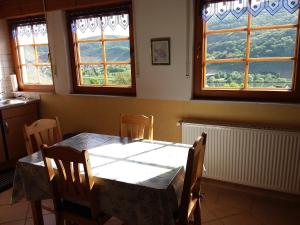 comedor con mesa, sillas y ventanas en Ferienwohnung Sommer, en Löf