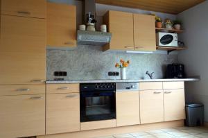 a kitchen with wooden cabinets and a stove at Eifelferienhaus Thome in Lissendorf