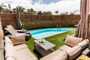 a backyard with a swimming pool and some chairs and a table at Paradise Beach House: piscina privada, playa 100m in Corralejo
