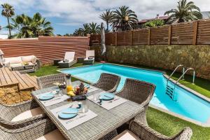 a patio with a table and chairs next to a swimming pool at Paradise Beach House: piscina privada, playa 100m in Corralejo