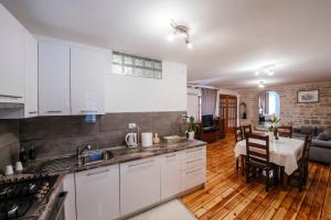 a kitchen with white cabinets and a living room at Heart of Town in Zadar