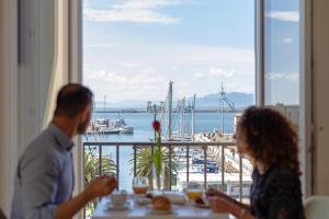 um homem e uma mulher sentados numa mesa com vista para o porto em Hotel Aristeo em Cagliari