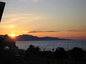 una puesta de sol sobre el océano con montañas en el fondo en Queen bedroom, en Terracina