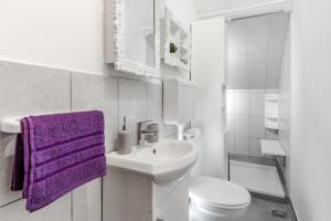 uma casa de banho branca com um lavatório e uma toalha roxa em Heavenly corner em Split
