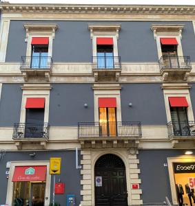 卡塔尼亞的住宿－Corte dei medici - Palace，蓝色的建筑,设有红色的窗户和阳台