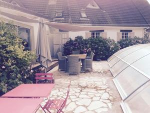 a patio with a table and chairs and an umbrella at le jardin adele in Drucat