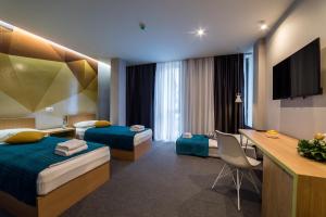a hotel room with two beds and a desk at Hotel Safir in Bihać