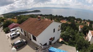 a white house with a car parked in a parking lot at Apartments Šudić in Njivice