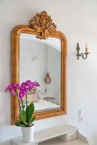 un espejo en una pared sobre una mesa con flores púrpuras en Ornos Blue, en Ornos