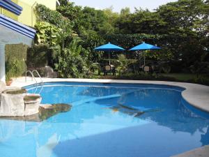 a swimming pool with blue water and two umbrellas at Hotel Playa Cristal in Catemaco