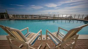 2 chaises assises en face d'une piscine dans l'établissement Family Friendly - Direct Oceanfront Sanibel 303, à Daytona Beach Shores