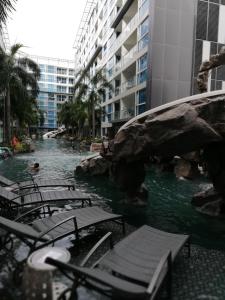 a swimming pool with chairs and a rock in a building at Centara Avenue apartment 711 in Pattaya