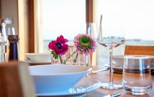 a table with a vase of flowers and glasses on it at Gud Jard Chalet Nr 18 - Design-Ferienhaus mit exklusiver Ausstattung in Pellworm +57 photos