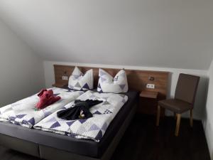 Bett mit Kleidung und Stuhl in einem Zimmer in der Unterkunft Pension Assmann in Langenbruck
