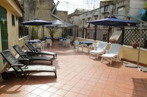 an outdoor patio with chairs and tables and umbrellas at Backpacker Naples in Naples