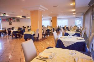 ein Esszimmer mit Tischen und Stühlen sowie blauer und weißer Bettwäsche in der Unterkunft Hotel Rivadoro-Spiaggia ombrellone e lettini inclusi-Piscina-Parcheggio in Martinsicuro