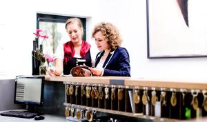 duas mulheres ao balcão com garrafas de vinho em Breuer's Rüdesheimer Schloss em Rüdesheim am Rhein