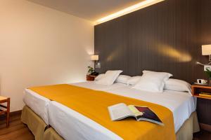 a bedroom with a large bed with two books on it at Hotel de Francia y París in Cádiz