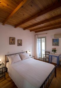 Schlafzimmer mit einem großen weißen Bett und Holzdecken in der Unterkunft Nostos Hotel in Chania