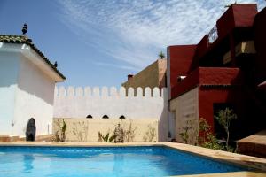 a swimming pool in front of a building with a white fence at Riad D'or meknes in Meknès