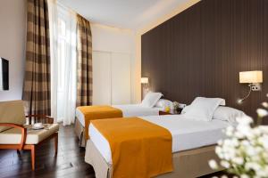 a hotel room with two beds and a chair at Hotel de Francia y París in Cádiz