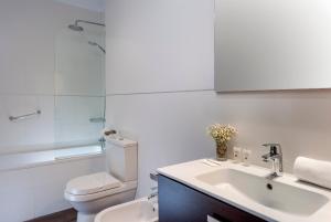 a white bathroom with a toilet and a sink at Hotel de Francia y París in Cádiz