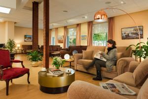 a woman sitting on a couch in a waiting room at Hotel de Francia y París in Cádiz