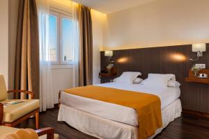 a hotel room with a large bed and a window at Hotel de Francia y París in Cádiz
