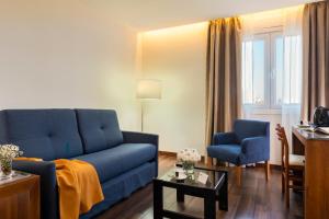 a living room with a blue couch and two chairs at Hotel de Francia y París in Cádiz