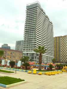 um edifício alto com cadeiras amarelas em frente em Orbi Residence Batumi em Batumi