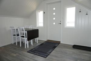 a dining room with a table and chairs and two windows at Varanger Fisherman's Shed in Varangerbotn