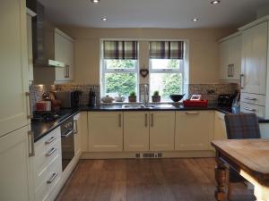 une cuisine avec des armoires blanches et une table en bois dans l'établissement Hazeldene Cottage, à Purmerend