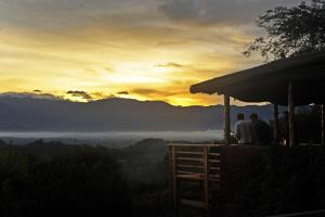 a group of people sitting at a table watching the sunset at Isunga Lodge in  Kibale Forest National Park