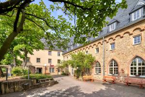 een groot bakstenen gebouw met banken ervoor bij Ev.Familienferien-und Bildungsstätte Ebernburg in Bad Münster am Stein-Ebernburg