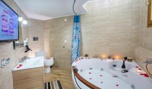 a bathroom with a tub and a toilet and a tv at Rent House Karavi in Iraklitsa