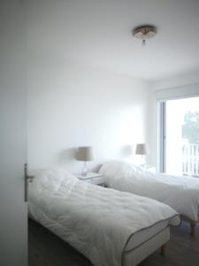 a white bedroom with a bed and a window at Le Splendid in La Baule