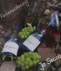 dos botellas de vino y dos copas de uva en Ferienwohnung Jo Secco, en Bruttig-Fankel