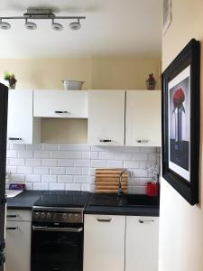 a kitchen with white cabinets and a black sink at Kawalerka - Jelenia Gora, dziel. Zabobrze in Jelenia Góra