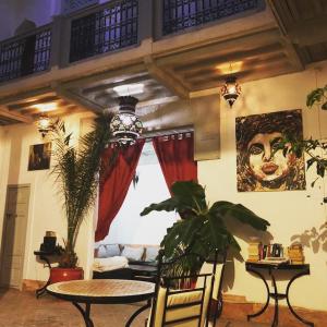 una sala de estar con mesa, plantas y una pintura en Dar Nabila, en Marrakech