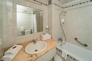 a bathroom with a sink and a tub and a mirror at Hotel Carabela Santa María in Mazagón +17 photos