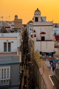a group of people walking down a street between buildings at Hotel de Francia y París in Cádiz