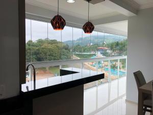 une cuisine avec une grande fenêtre donnant sur une piscine dans l'établissement Apartamento 602 Edifício Thermas Palace, à Piratuba