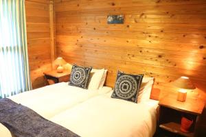 two beds in a room with wooden walls at First Tracks Madarao in Iiyama