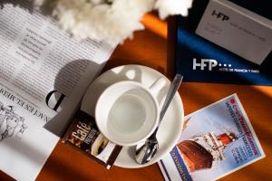 a cup of coffee next to a newspaper and a book at Hotel de Francia y París in Cádiz